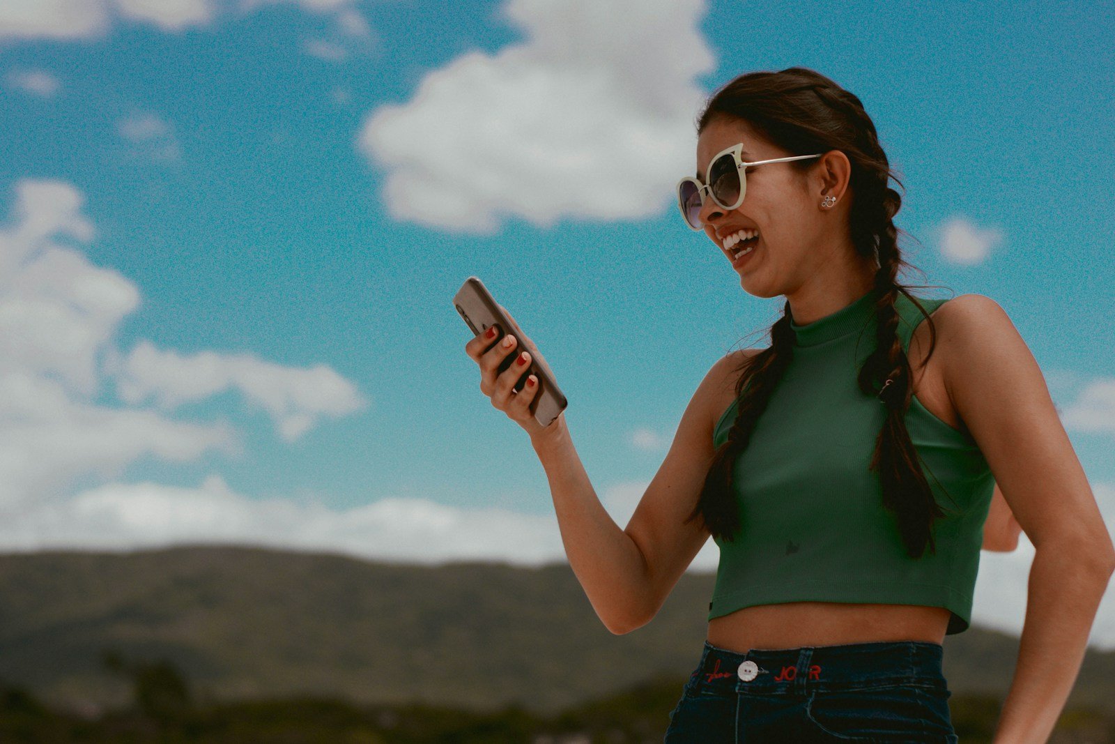 Photo by Carol Magalhães woman in green tank top holding smartphone during daytime